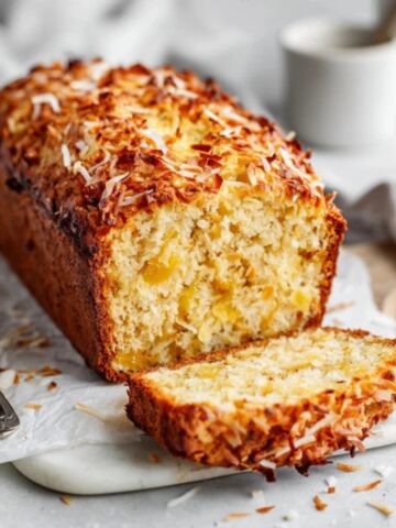 Moist pineapple coconut bread loaf with toasted coconut topping on a white kitchen counter