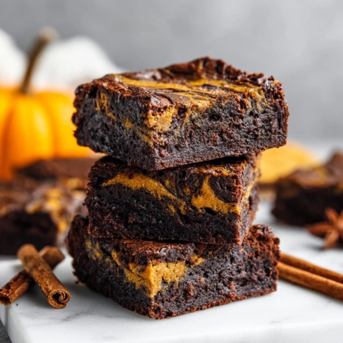 fudgy pumpkin brownies with chocolate and pumpkin swirl on white counter