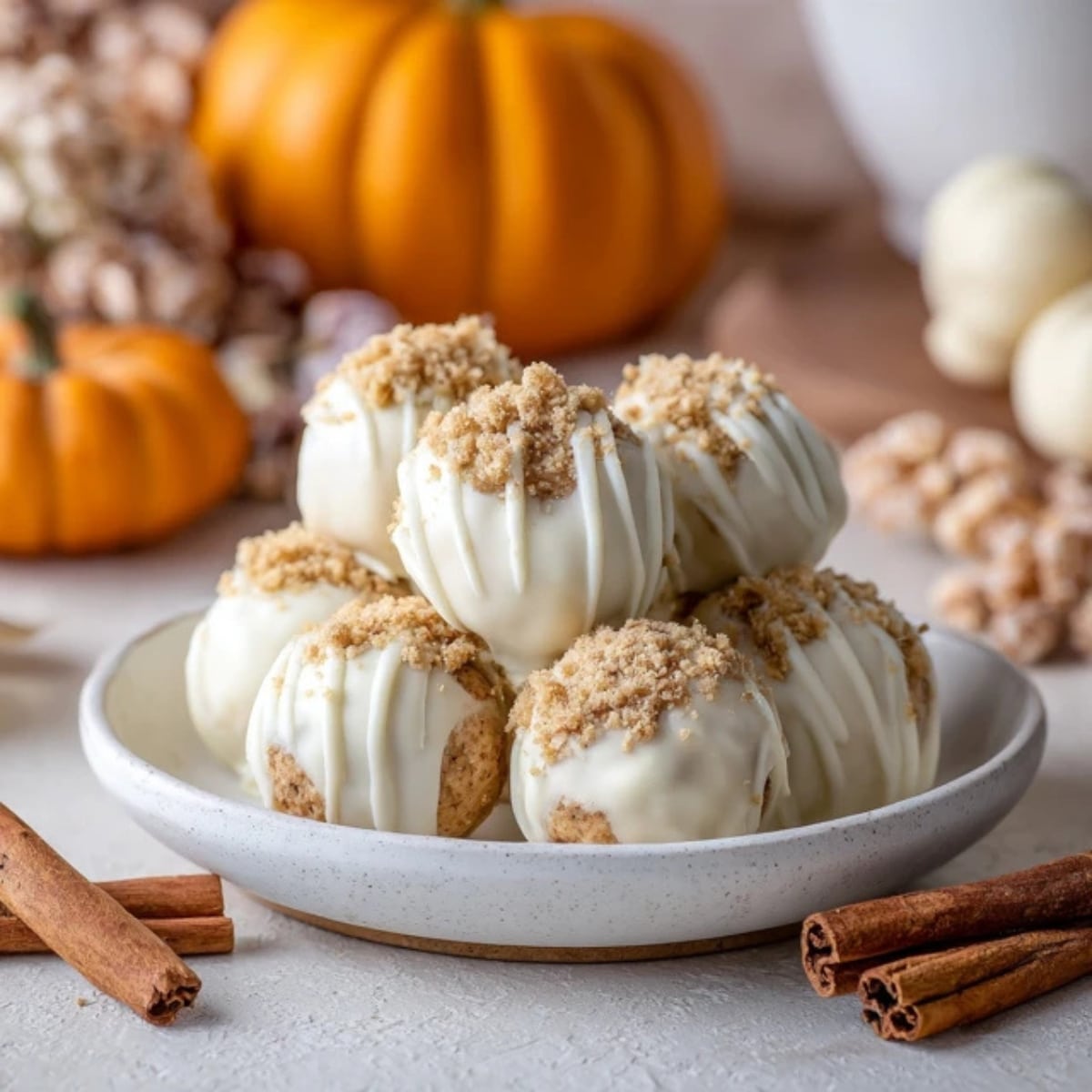 No-bake pumpkin cheesecake balls coated in white chocolate on a kitchen counter