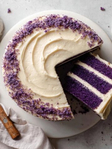 Purple velvet cake with cream cheese frosting on white counter