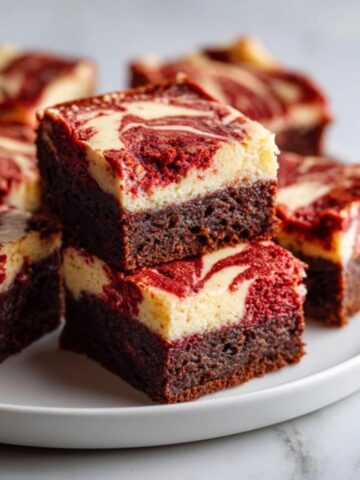 Fudgy red velvet cheesecake brownies with creamy cheesecake swirl on white plate