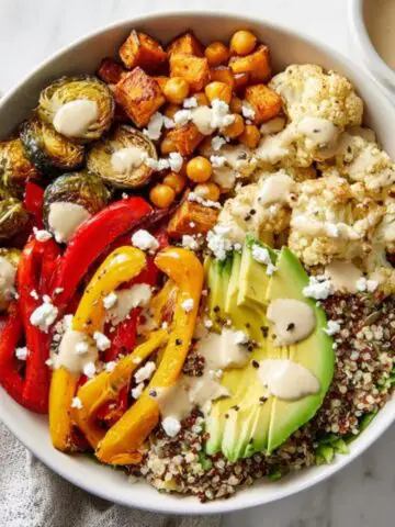 roasted veggie bowl with quinoa and tahini dressing on white counter