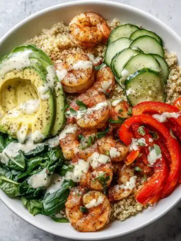 healthy shrimp quinoa bowl with fresh vegetables on white counter
