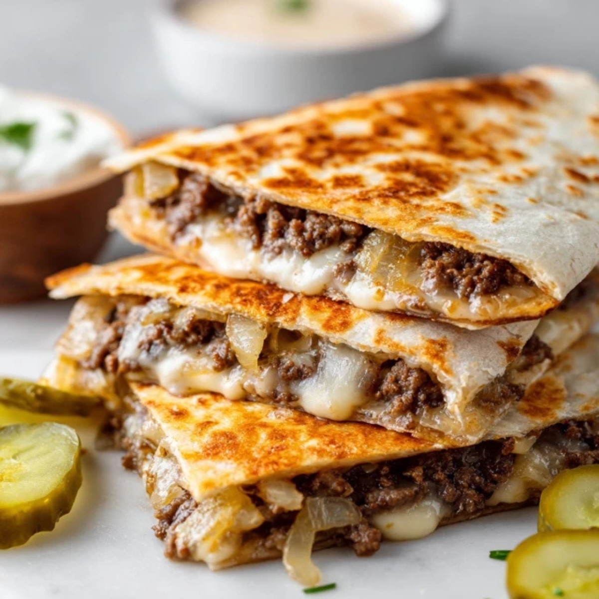 crispy smashburger quesadillas with melted cheese and caramelized onions on white kitchen counter