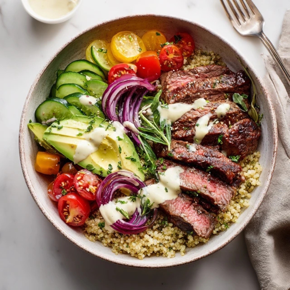 Healthy steak quinoa bowl with avocado and veggies on white counter