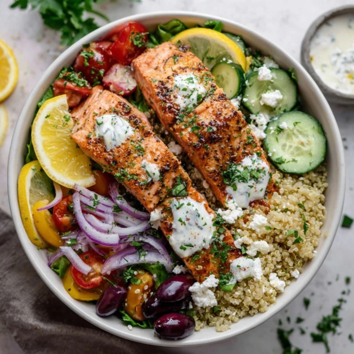 Mediterranean salmon bowl with quinoa, veggies, and feta on white counter