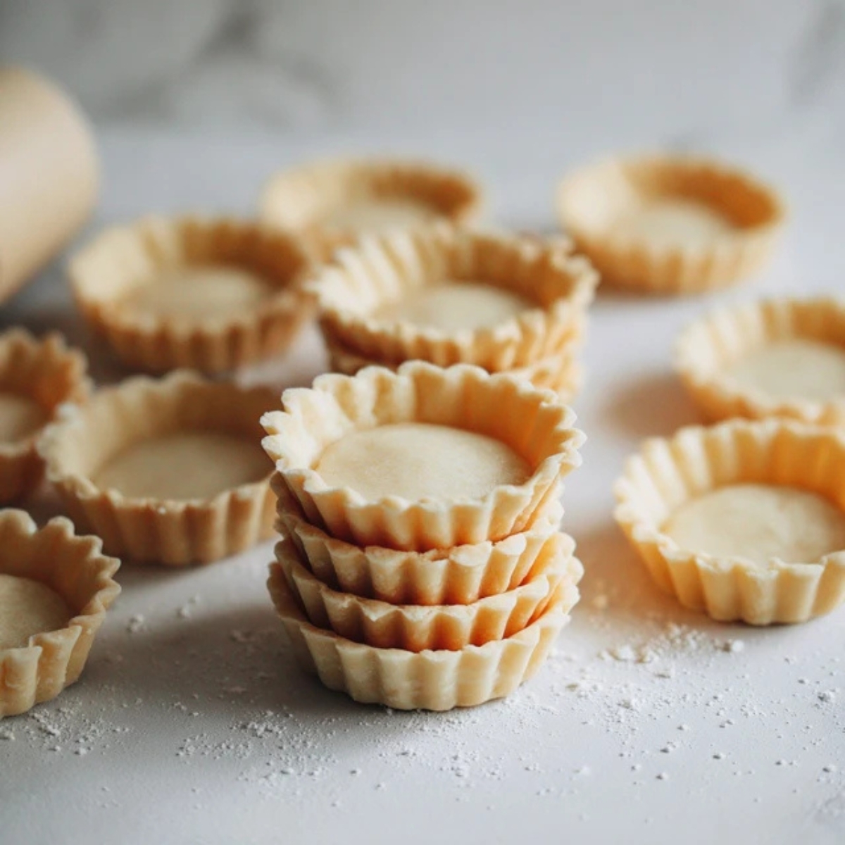 Homemade mini tart shells on white kitchen counter
