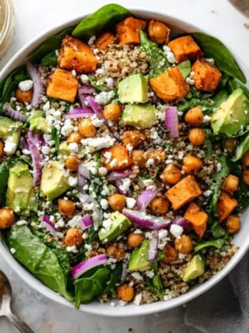 Colorful sweet potato quinoa salad with chickpeas and avocado on a white kitchen counter