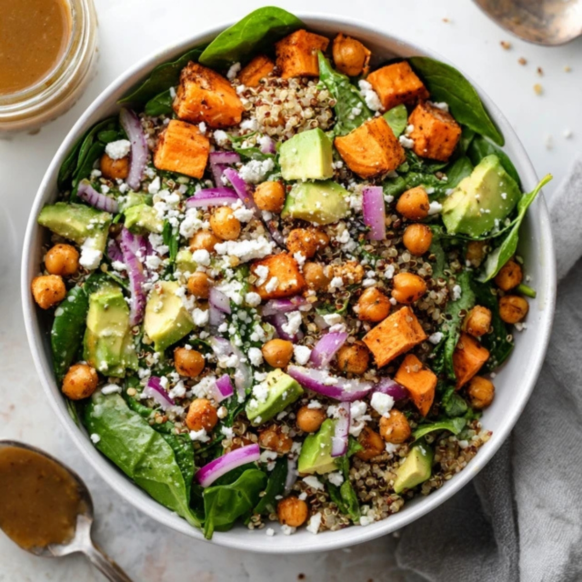 Colorful sweet potato quinoa salad with chickpeas and avocado on a white kitchen counter