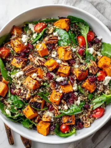 Homemade sweet potato salad with feta, quinoa, and greens on a white kitchen counter